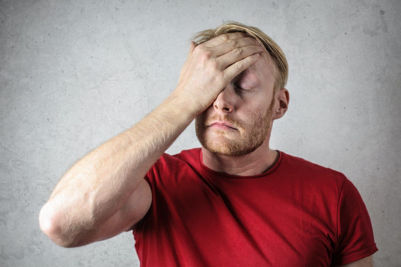 Frustrated man face-palming.