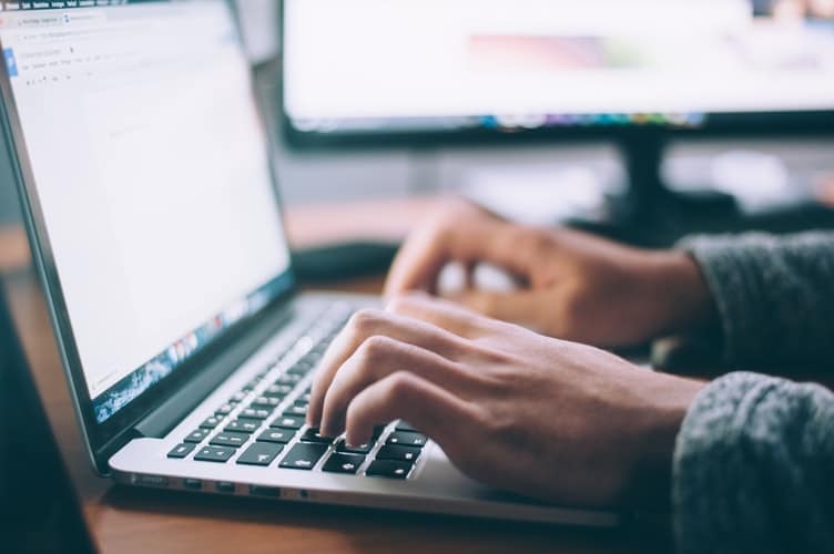 A close-up of someone's hands typing on a laptop.