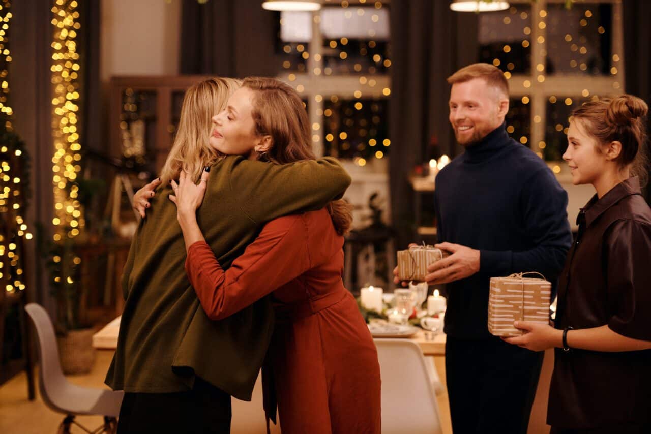 Family members hugging and exchanging gifts during a holiday celebration.