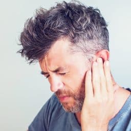 Man with tinnitus pressing his ear.