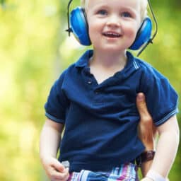 Cute little boy lifted up by his father while wearing noise-canceling headphones