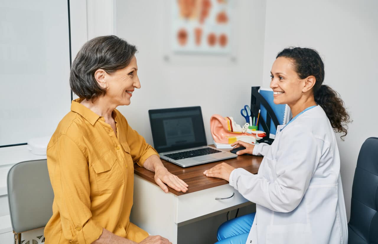 A senior woman talking to her audiologist about hearing loss.