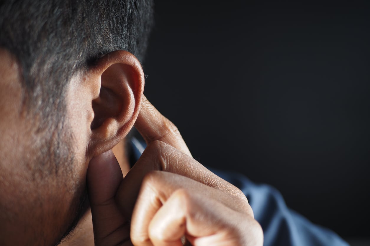 Close up of a man holding his hand to his ear.